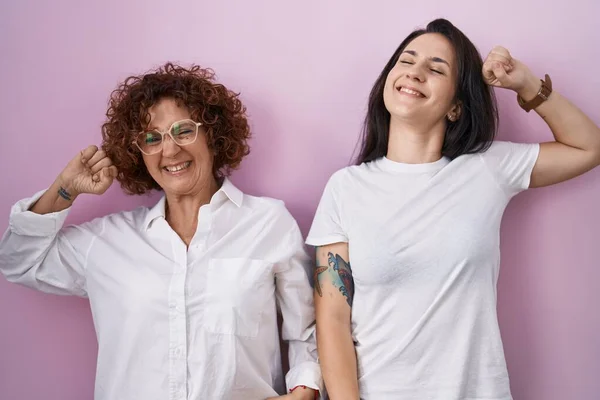 Hispanic Mother Daughter Wearing Casual White Shirt Pink Background Stretching — 스톡 사진