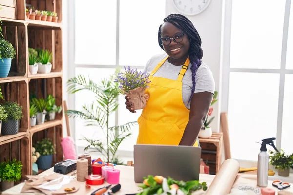 stock image African american woman florist using laptop holding plant at florist