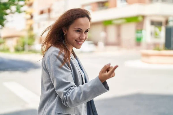 Young woman executive doing coming gesture with finger at street