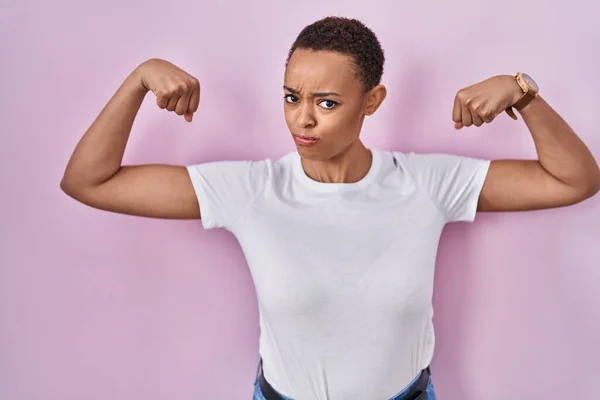 美丽的非洲裔美国女人站在粉红的背景上 露出胳膊肌肉 露出自豪的笑容 健身概念 — 图库照片
