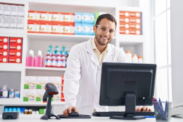 年轻的药剂师带着自信的笑容在药店用电脑 — 图库照片