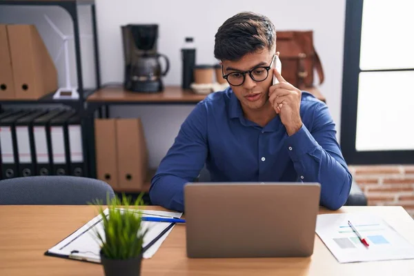 Young Hispanic Man Business Worker Using Laptop Talking Smartphone Office — Foto de Stock