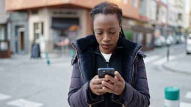 Sokakta akıllı telefon kullanan Afro-Amerikalı kadın.