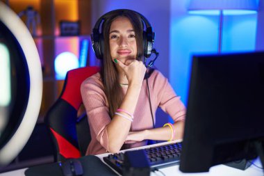 Genç İspanyol kadın video oyunları oynuyor kameraya bakıyor kollarını kavuşturup gülümsüyor ve çenesini kaldırıyor. Olumlu düşünmek. 