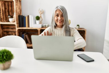 Orta yaşlı, kır saçlı, gülümseyen bir kadın.