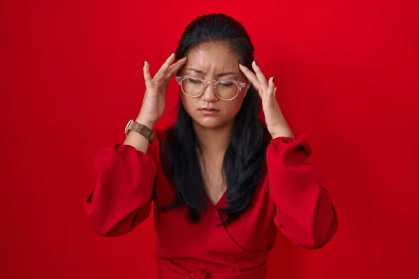 アジアの若い女性の頭の上に手で赤の背景に立って 頭痛の種ので ストレス 片頭痛 — ストック写真