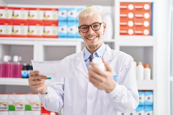 Young Caucasian Man Pharmacist Holding Pills Bottle Reading Prescription Pharmacy — Zdjęcie stockowe