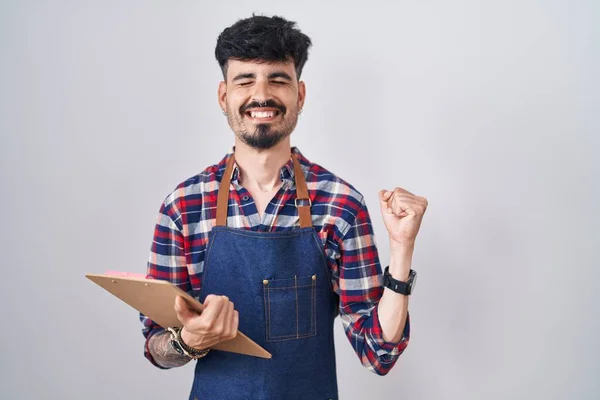 Young Hispanic Man Beard Wearing Waiter Apron Holding Clipboard Very — Stock Photo, Image