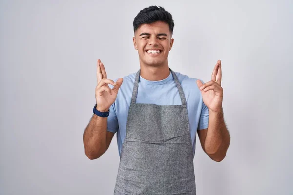 Hispanic Ung Man Bär Förkläde Över Vit Bakgrund Gestikulerande Finger — Stockfoto