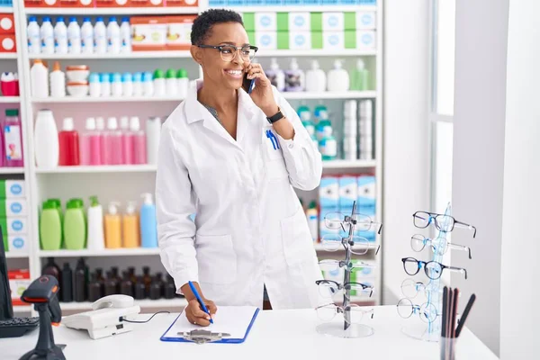African American Woman Pharmacist Talking Smartphone Writing Document Pharmacy — Stockfoto