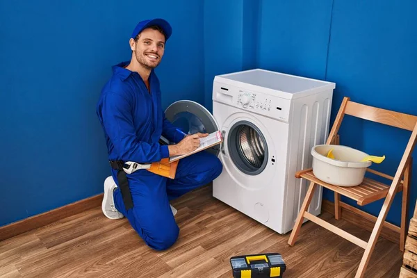 Young Hispanic Man Technician Repairing Washing Machine Writing Document Laundry — Foto Stock