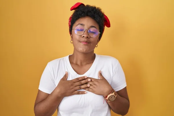 Sarı Arka Planda Dikilen Genç Afro Amerikalı Kadın Elleri Göğsünde — Stok fotoğraf