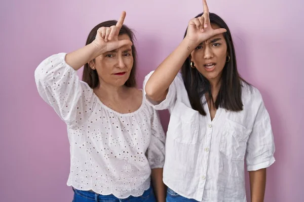 西班牙裔母亲和女儿一起用手指在额头上取笑那些做失败者动作的人 嘲笑和侮辱 — 图库照片