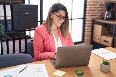 Ofiste çalışan genç İspanyol iş kadını laptopu kullanıyor.