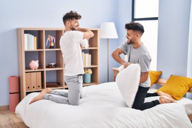 Yatak odasında yastıkla kavga eden genç bir çift.