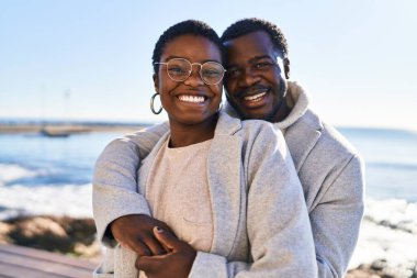 Erkek ve kadın çift sahilde birbirlerine sarılıyorlar.