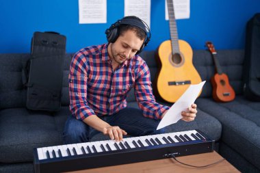 Young man musician playing piano keyboard at music studio