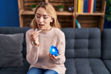 Evdeki kanepede oturan görünmez hizayı tutan genç bir kadın.