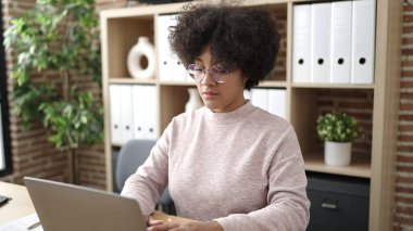 Ofiste çalışan genç Afro-Amerikan iş kadını laptopu kullanıyor.