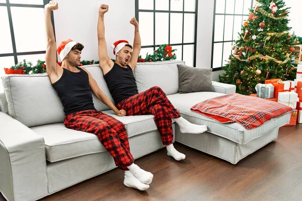 二つのヒスパニック系男性カップルYawningと伸張腕によって座ってクリスマスツリーに家 — ストック写真