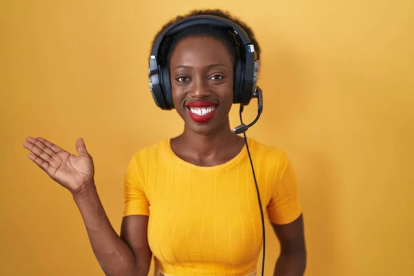 Afrikaanse Vrouw Met Krullend Haar Staande Gele Achtergrond Met Koptelefoon — Stockfoto