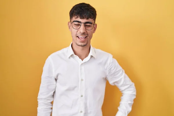 Jovem Hispânico Homem Sobre Fundo Amarelo Piscando Olhando Para Câmera — Fotografia de Stock