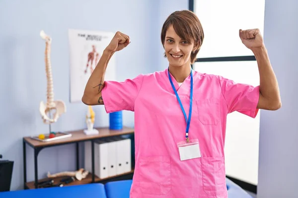在复健诊所工作的布鲁内特妇女露出胳膊肌肉微笑 感到自豪 健身概念 — 图库照片