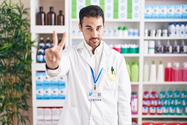 Красивый Латиноамериканец Работающий Аптеке Показывающий Пальцем Номер Два Улыбаясь Уверенно — стоковое фото
