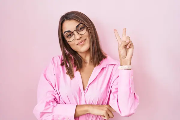 Jonge Spaanse Vrouw Met Een Bril Een Roze Achtergrond Glimlachend — Stockfoto
