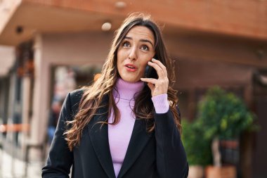 Genç İspanyol kadın gülümsüyor. Kendine güveniyor. Akıllı telefondan konuşuyor.