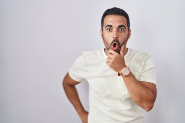 Tecrit edilmiş arka planda duran İspanyol sakallı adam elleri çenesinde olan inanması güç, şaşırmış ve şaşırmış bir ifade takınıyor. 