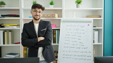 Genç Arap adam matematik dersi veriyor. Üniversite sınıfında kollarını kavuşturup el kol hareketi yapıyor.