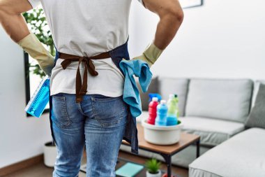 Young hispanic man on back view holding sprayer at home