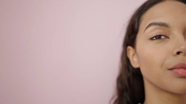 Genç, güzel, İspanyol bir kadın izole edilmiş pembe arka planda ciddi bir ifadeye sahip.