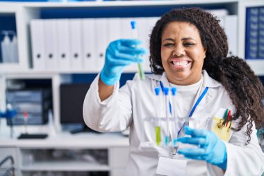 Laboratuvarda test tüpleri tutan Afrikalı Amerikalı kadın bilim adamı.