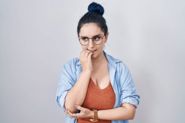 Beyaz arka planda duran mavi saçlı genç modern kız elleri ağız ısıran tırnaklarıyla stresli ve gergin görünüyor. anksiyete. 