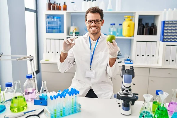 Young Hispanic Man Working Scientist Laboratory Holding Apple Smiling Happy — Stock fotografie