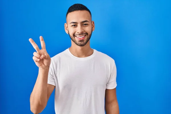 Junger Hispanischer Mann Der Vor Blauem Hintergrund Steht Lächelnd Mit — Stockfoto