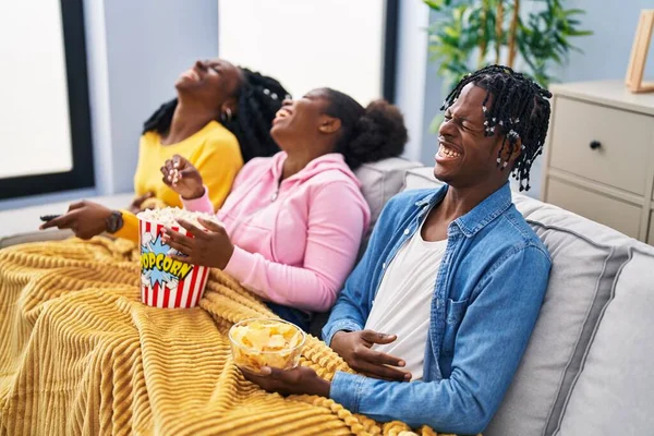 African american friends watching movie sitting on sofa at home