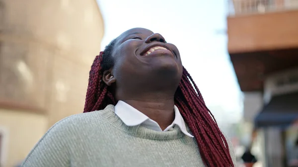自信を持って笑いながら髪を編んだアフリカの女性が通りを見上げ — ストック写真