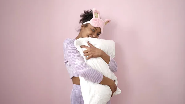 アフリカ系アメリカ人女性身に着けています睡眠マスク巨大枕上の隔離されたピンクの背景 — ストック写真
