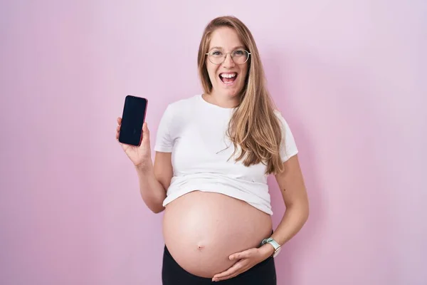 Mladá Těhotná Žena Ukazuje Břicho Drží Smartphone Úsměvem Hlasitě Zasměje — Stock fotografie