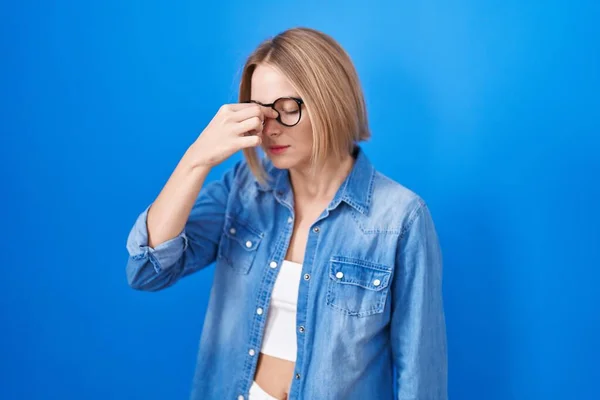 青い背景に立って若い白人女性疲れ鼻や目の疲労感や頭痛をこすり ストレスとフラストレーションの概念 — ストック写真