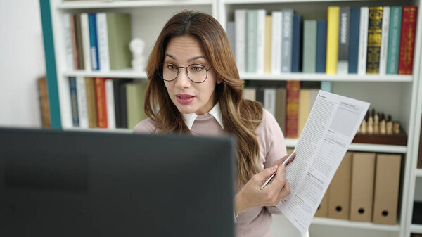 Молодая красивая латиноамериканка с видеозвонком показывает документы в библиотечном университете