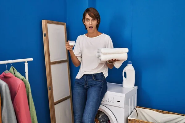 きれいな洗濯を持っているブルネットの女性は恐れて 驚きと驚きの表情でショックを受けました 恐怖と興奮した顔 — ストック写真