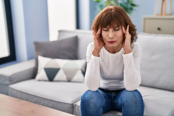 stock image Middle age woman suffering for headache sitting on sofa at home