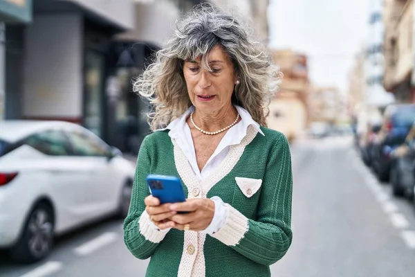 スマートフォンを路上で使う中年女性 — ストック写真