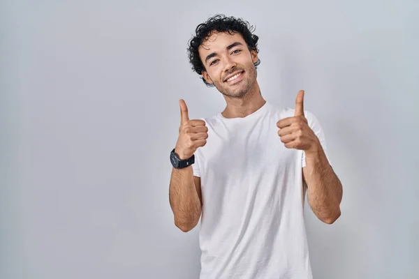 孤立した背景の成功の印の上に立つヒスパニック系の男は手で積極的なジェスチャーをし 親指を笑顔と幸せ 陽気な表情と勝者のジェスチャー — ストック写真