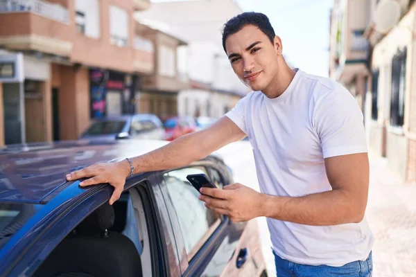 Young Hispanic Man Using Smartphone Leaning Car Street — стоковое фото