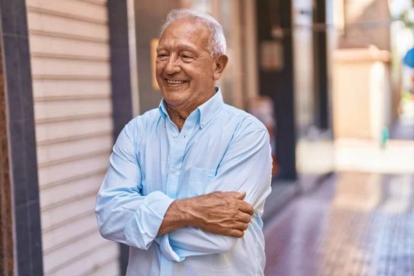 stock image Senior grey-haired man smiling confident standing with arms crossed gesture at street